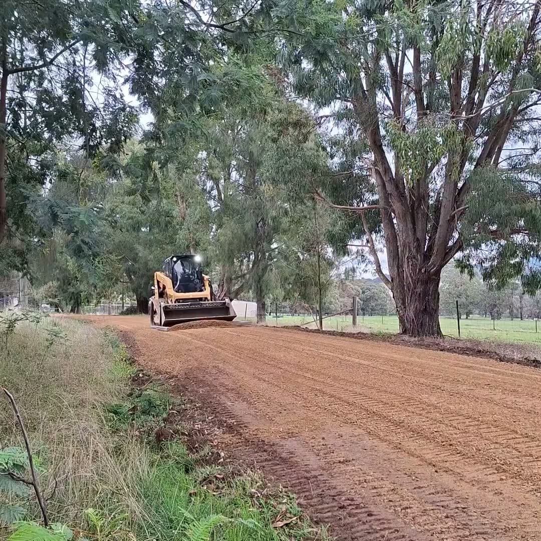 skid steer grading a crushed rock driveway on a rural block, earthworks